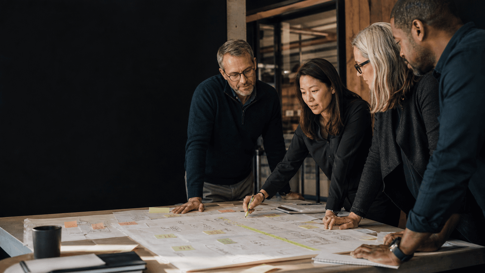 A cross-functional team mapping roles, handoffs, and decisions around a shared work surface